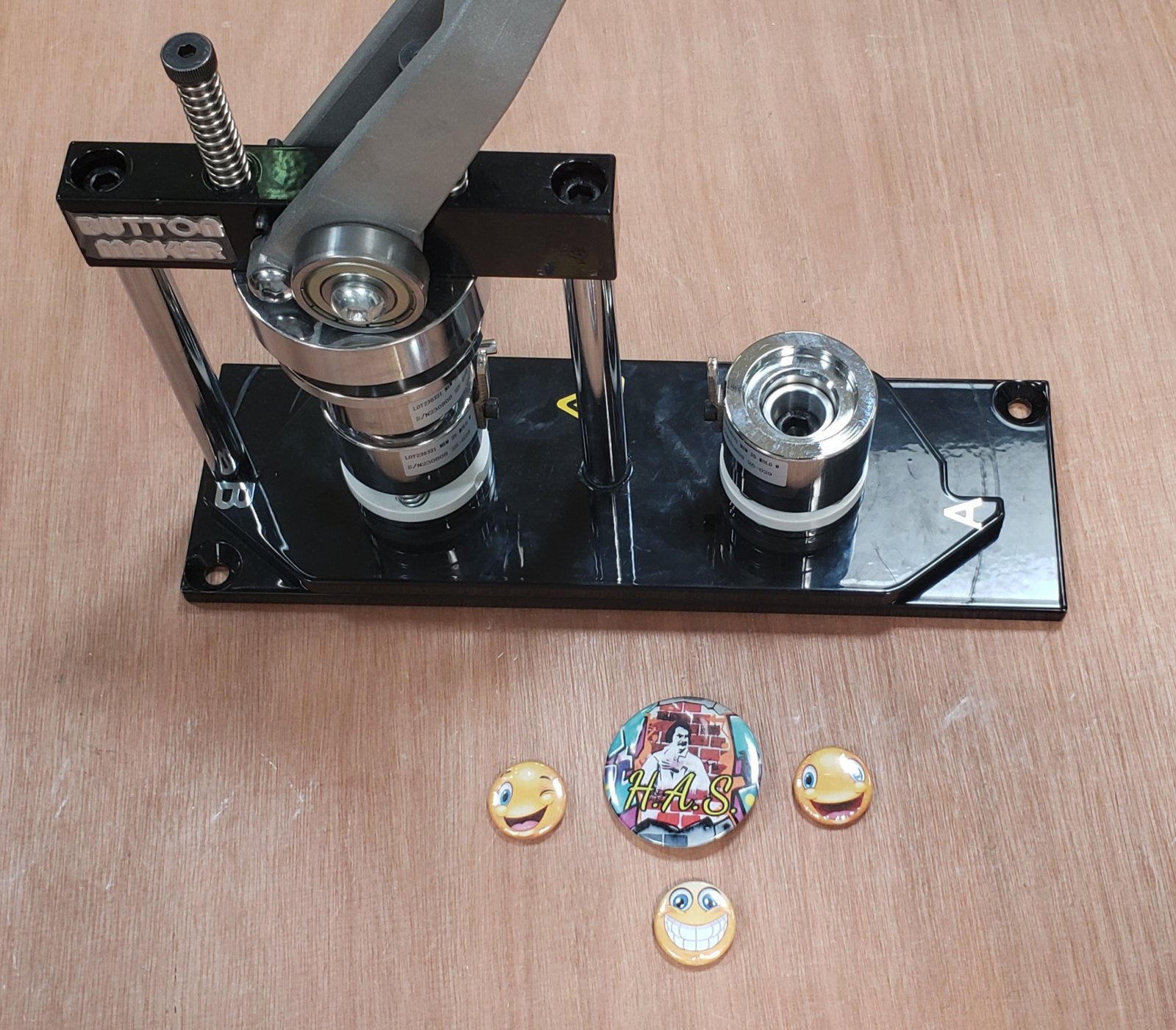 Gros plan sur la machine à badges avec 4 badges génériques en exemple.