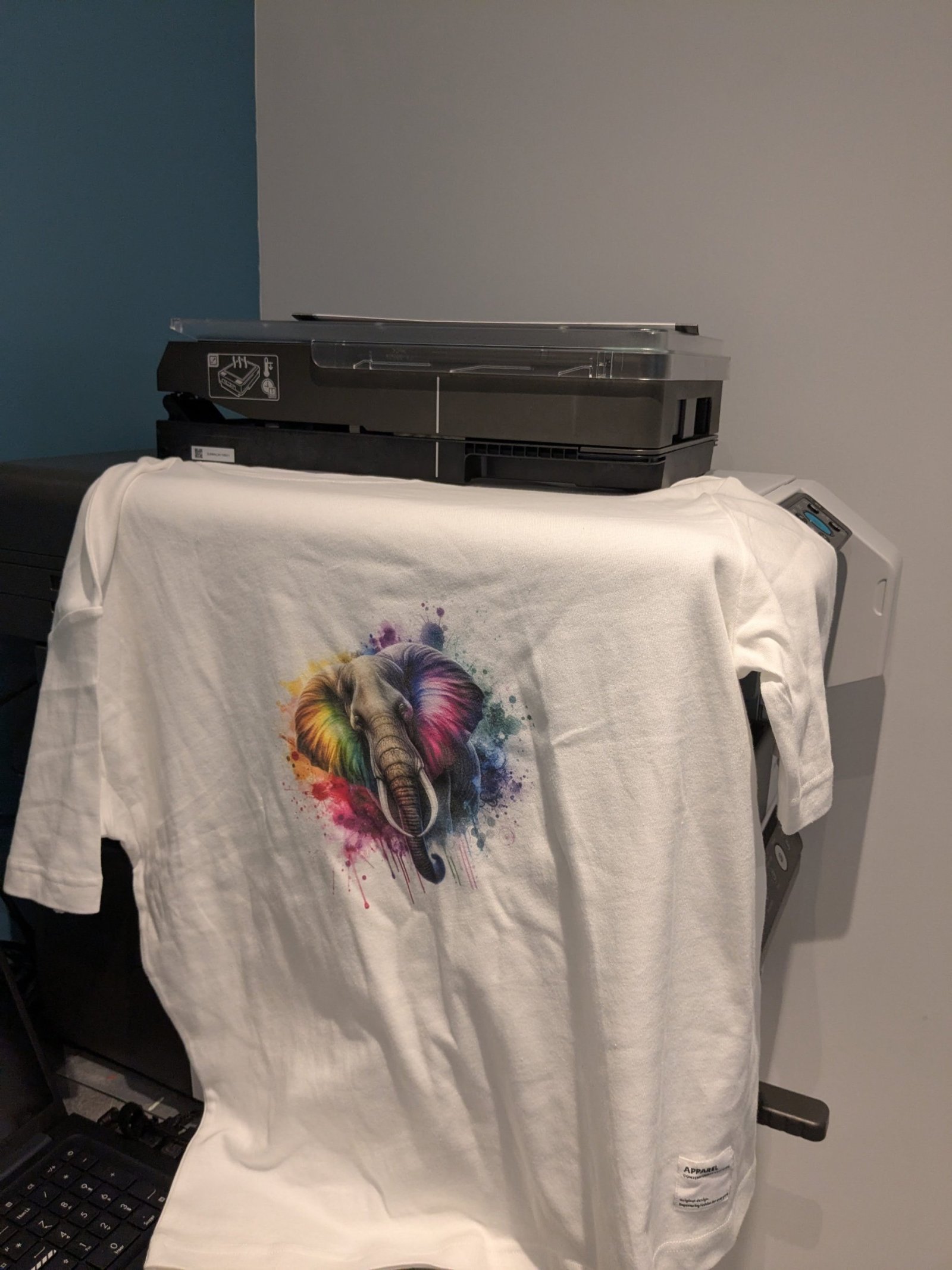 Plan sur un tshirt avec une illustration très coloré imprimé sur celui-ci par la machine qui est derrière.