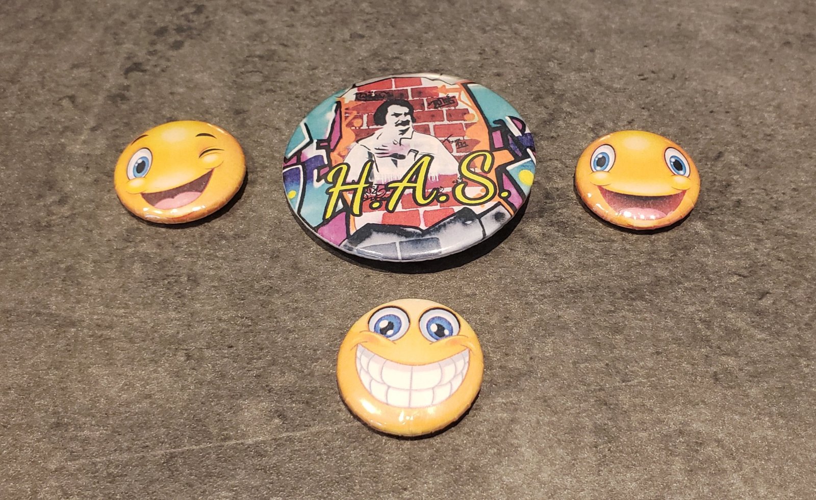 4 badges réalisé au collège : 3 petits avec smiley et un un moyen avec Honoré de Balzac dessus.